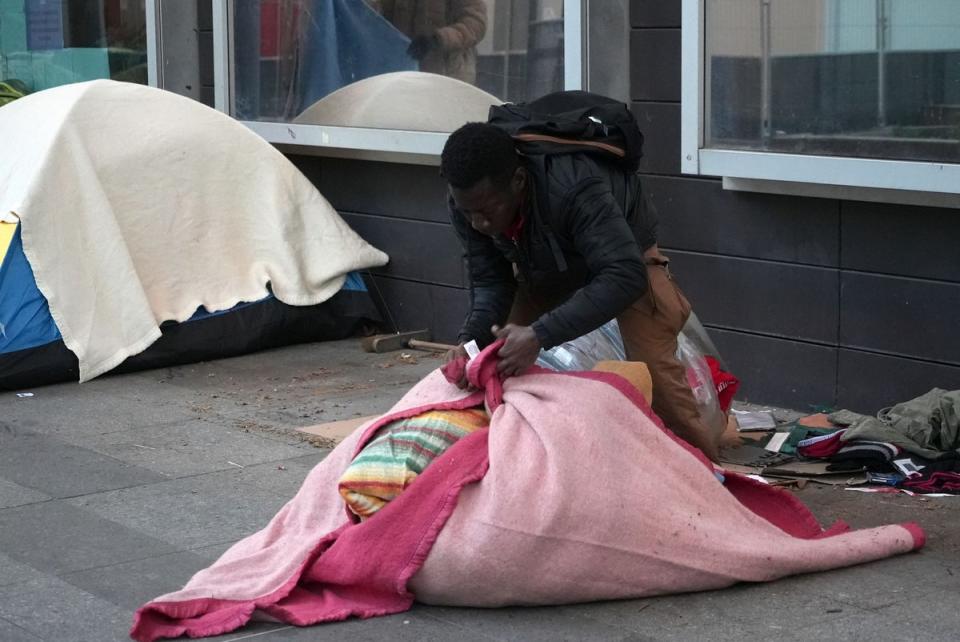 A migrant packs his belongings at a makeshift camp in Paris, early on Tuesday, April 23 (AP)