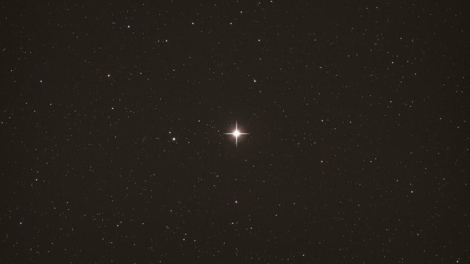     A bright star in the middle of the screen against the dark backdrop of space. 