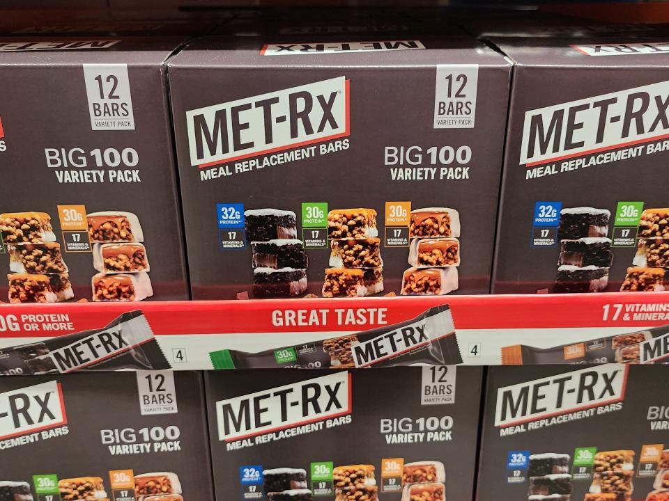 Gray boxes of Met-RX meal replacement bars with pictures of bars of various flavors on the box