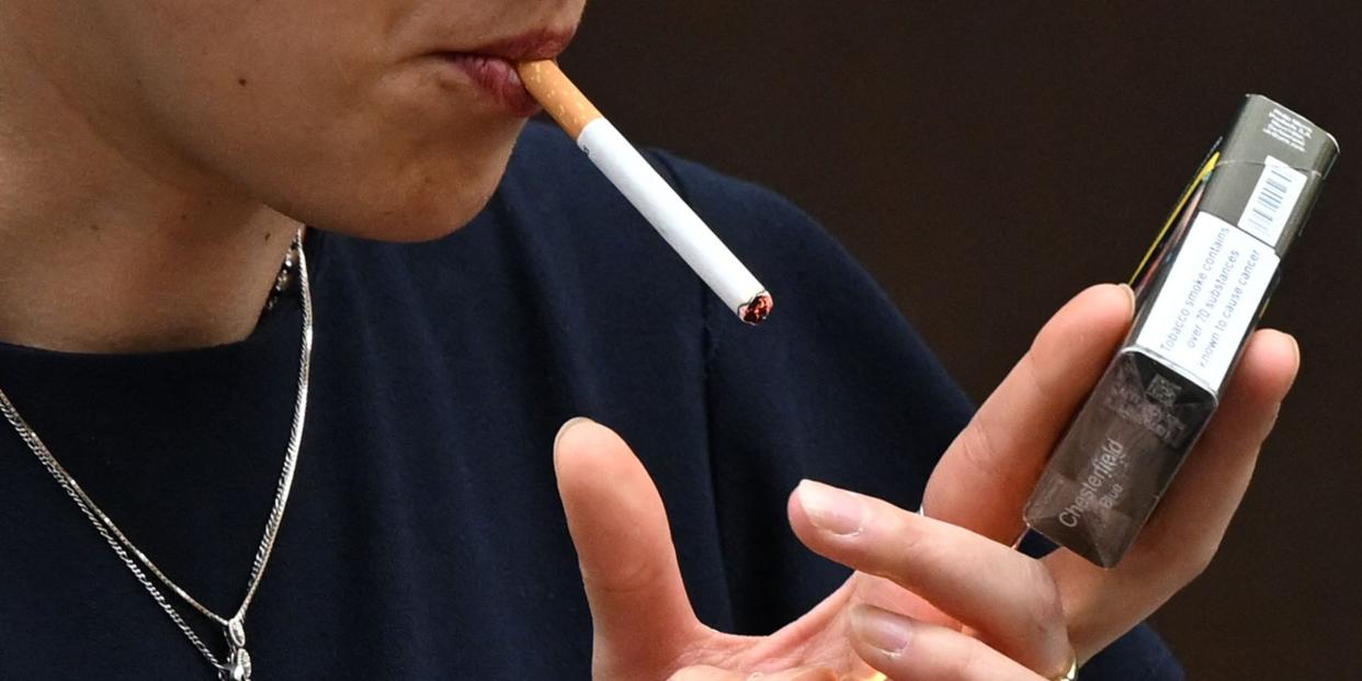 A woman is seen smoking a cigarette in central London on June 9, 2022. - The age at which people can buy tobacco in England should rise by one each year until it becomes a "smoke-free" society, a government-commissioned review recommended Thursday. (Photo by JUSTIN TALLIS / AFP) (Photo by JUSTIN TALLIS/AFP via Getty Images)