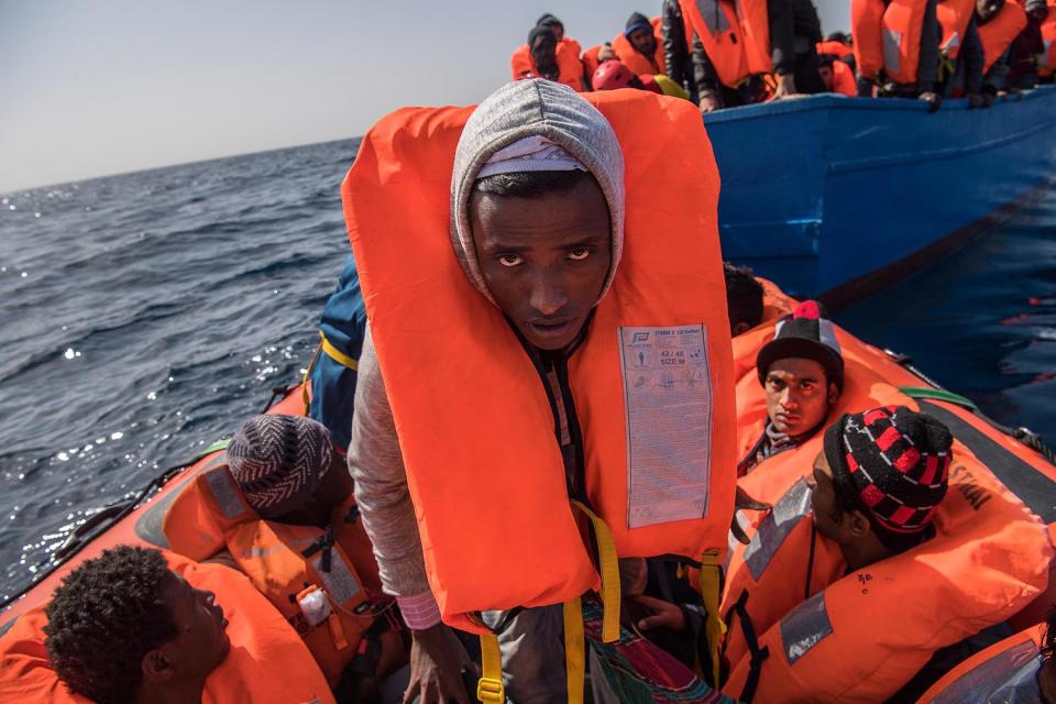 <p>A man looks into the camera as migrants and refugees are assisted by members of the Spanish NGO Proactiva Open Arms as they crowd on board of a wooden boat sailing out of control at 20 miles (38 km) north of Sabratha, Libya on Feb. 18, 2017 at Sea. (Photo: David Ramos/Getty Images) </p>