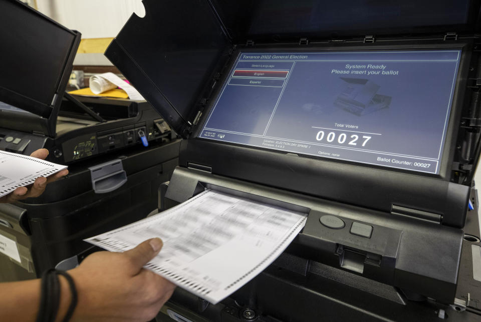 FILE - Torrance County administrative assistant clerk Kevin Pham introduces a ballot in a counting machine during a testing of election equipment with local candidates and partisan officers in Estancia, N.M., Sept. 29, 2022. Unlike in many other countries, elections in the U.S. are highly decentralized, complex and feature a long list of races on the ballot, from president or Congress all the way down to local ballot measures or town council seats. Rules also vary greatly by state. (AP Photo/Andres Leighton, File)