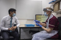 Britian's Chancellor of the Exchequer Rishi Sunak, left, sits, during a visit to Imperial Clinic Research Facility at Hammersmith Hospital, where he met staff and was instructed on research techniques, to mark the announcement of his Spending Review, in London, Wednesday, Nov. 25, 2020. (Jack Hill/Pool Photo via AP)