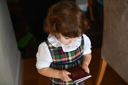 Elena, who is two years and seven-months old, and the eldest daughter of Maria and Adi, holds up British passports belonging to her and her sister, at home in London, Britain, February 17, 2019. REUTERS/Alecsandra Dragoi
