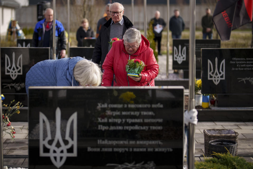 A crying relative waits to place flowers on the grave of a fallen Ukrainian serviceman during a commemoration for the victims of the Russian occupation at a cemetery in Bucha, Ukraine, Sunday, March 31, 2024. Ukrainians mark the second anniversary of the liberation of Bucha, during which Russian occupation left hundreds of civilians dead in the streets and in mass graves in Bucha during the initial months of the Russian invasion in 2022. (AP Photo/Vadim Ghirda)