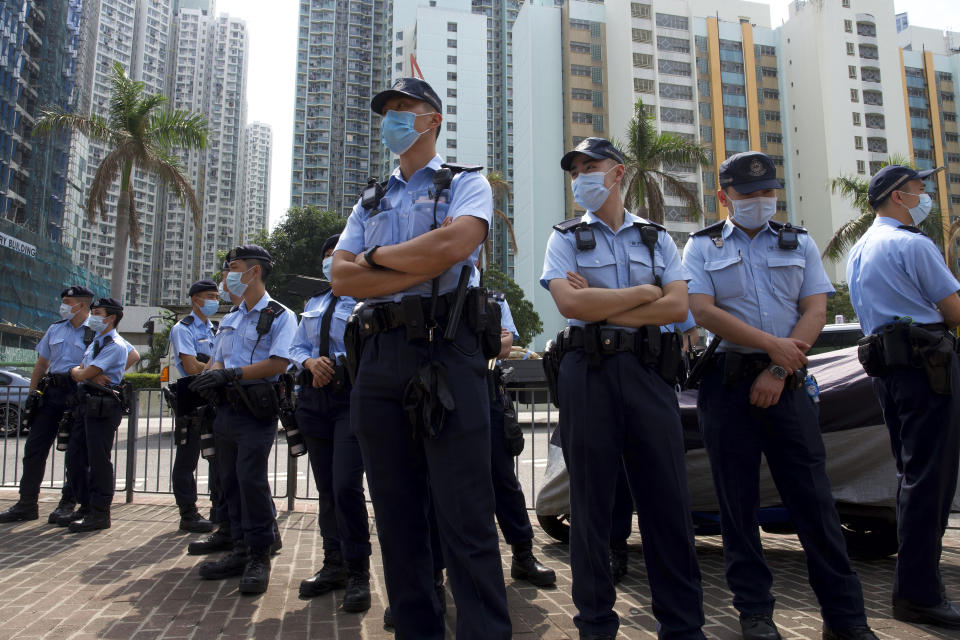 Police officers stand guard as many supporters queue up outside a court to try to get in for a hearing in Hong Kong Monday, March 1, 2021. Pro-democracy activists detained by police on Sunday on charges of conspiracy to commit subversion under the sweeping national security law, are expected to appear in court. (AP Photo/Vincent Yu)