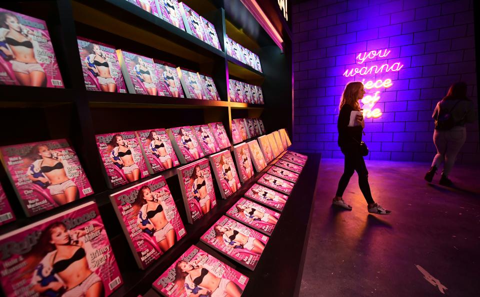 A woman walks past a display with images of Rolling Stone magazine at 