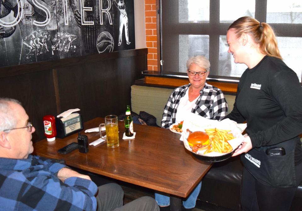 A waitress at Beef O'Brady's serves up a burger at the restaurant on South Market Street at Henry Street in Wooster.