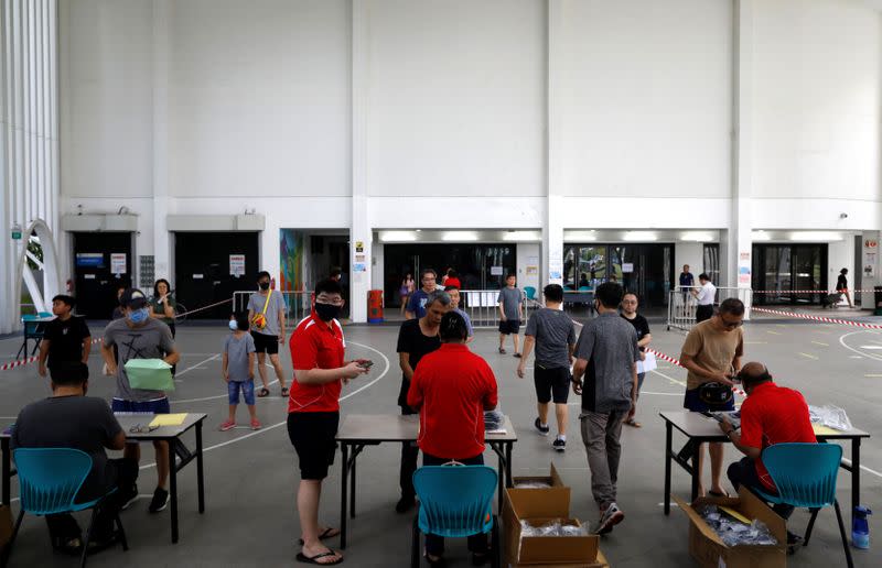 Residents receive free reusable masks distributed by the government at a community center, as stricter measures are announced to combat the outbreak of the coronavirus disease (COVID-19) in Singapore