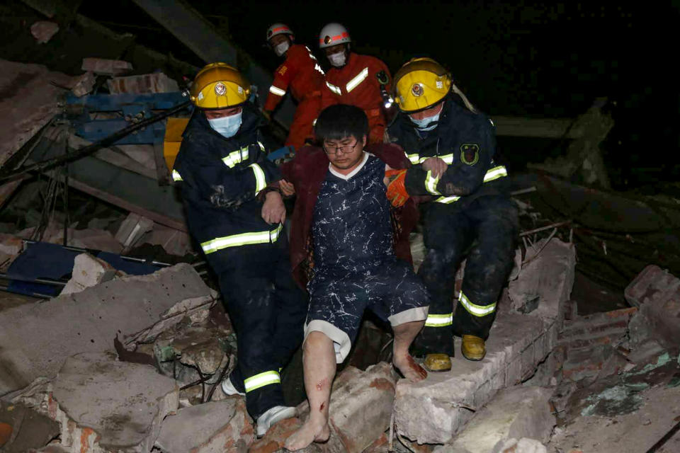 A man (C) is helped out of the rubble of a collapsed hotel by rescuers in Quanzhou, in China's eastern Fujian province on March 7, 2020. - Around 70 people were trapped after the Xinjia Hotel collapsed on March 7 evening, officials said. (Photo by STR / AFP) / China OUT (Photo by STR/AFP via Getty Images)