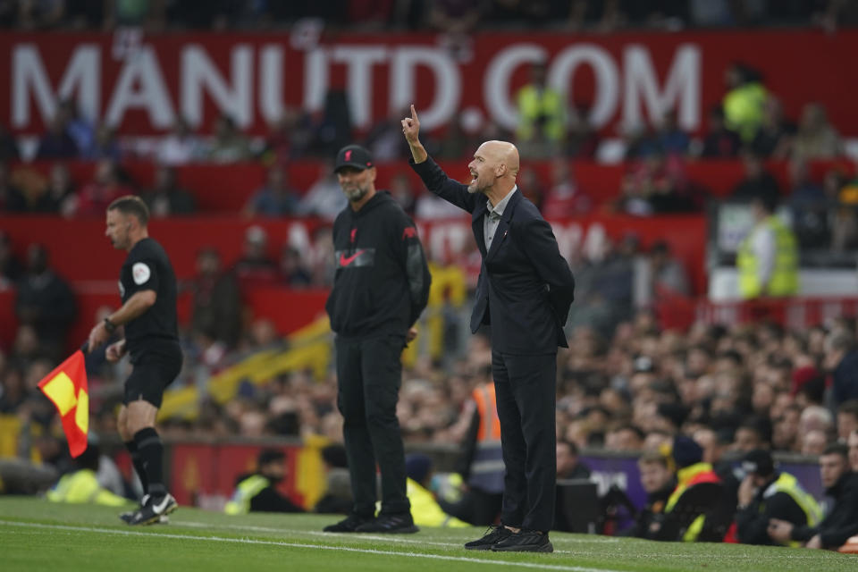 Manchester United's head coach Erik ten Hag gestures as Liverpool's manager Jurgen Klopp watches him in background during the English Premier League soccer match between Manchester United and Liverpool at Old Trafford stadium, in Manchester, England, Monday, Aug 22, 2022. (AP Photo/Dave Thompson)