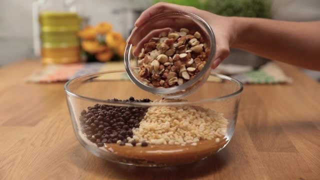 Adding chopped nuts to granola bar mixture