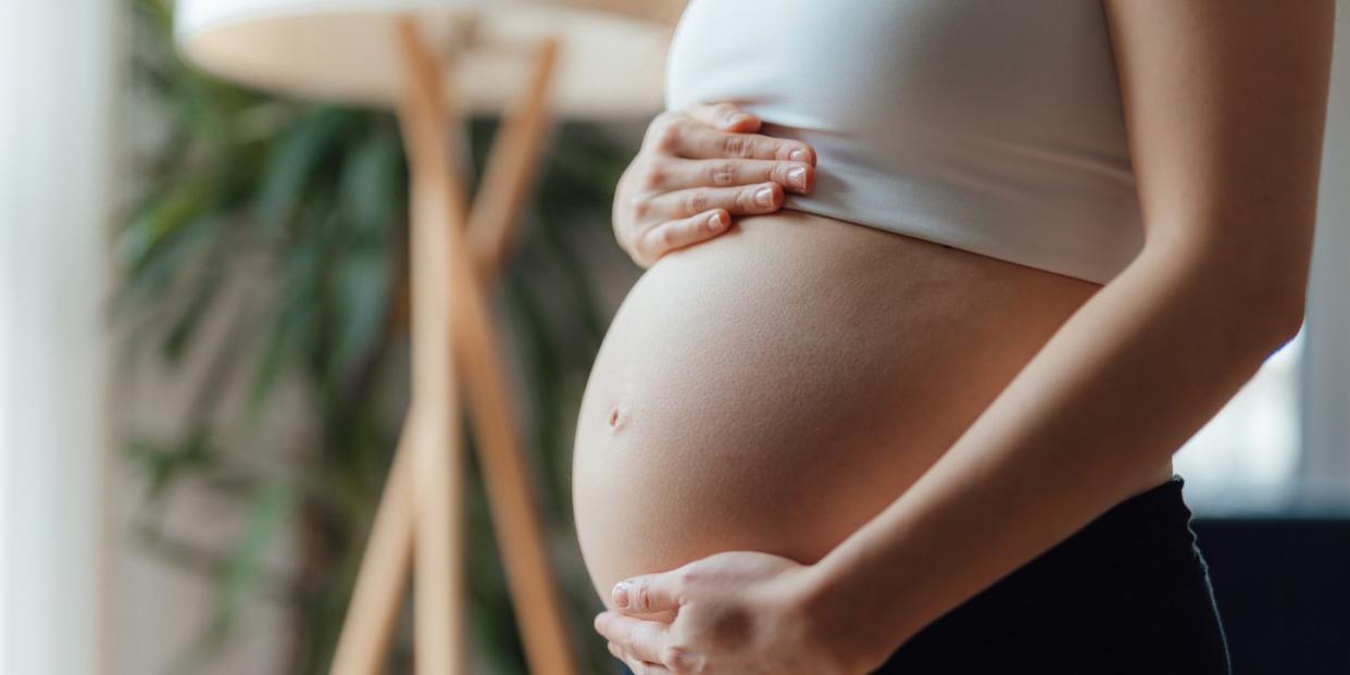 side view close up of pregnant woman touching her belly