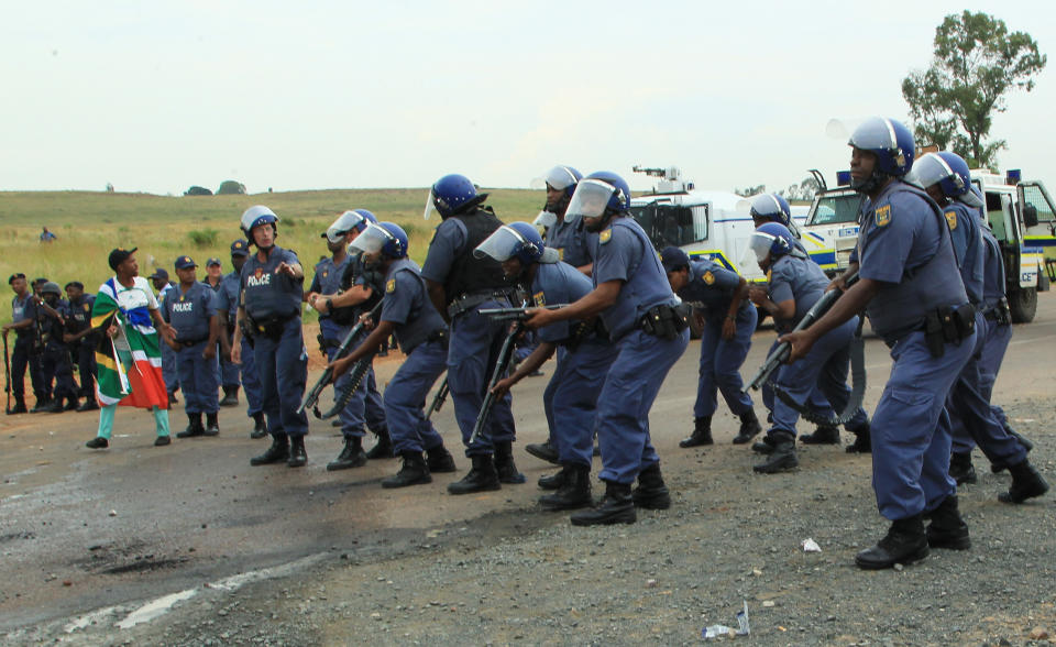 Police officers stand on guard as residents protest at Zithobile in Bronkhorstspruit, near Pretoria, South Africa, Thursday, Feb. 6, 2014. Demonstrators set several buildings, including a clinic, on fire on Wednesday in the Bronkhorstspruit district, east of the capital, Pretoria, to protest what they say are high electricity prices. (AP Photo/Themba Hadebe)