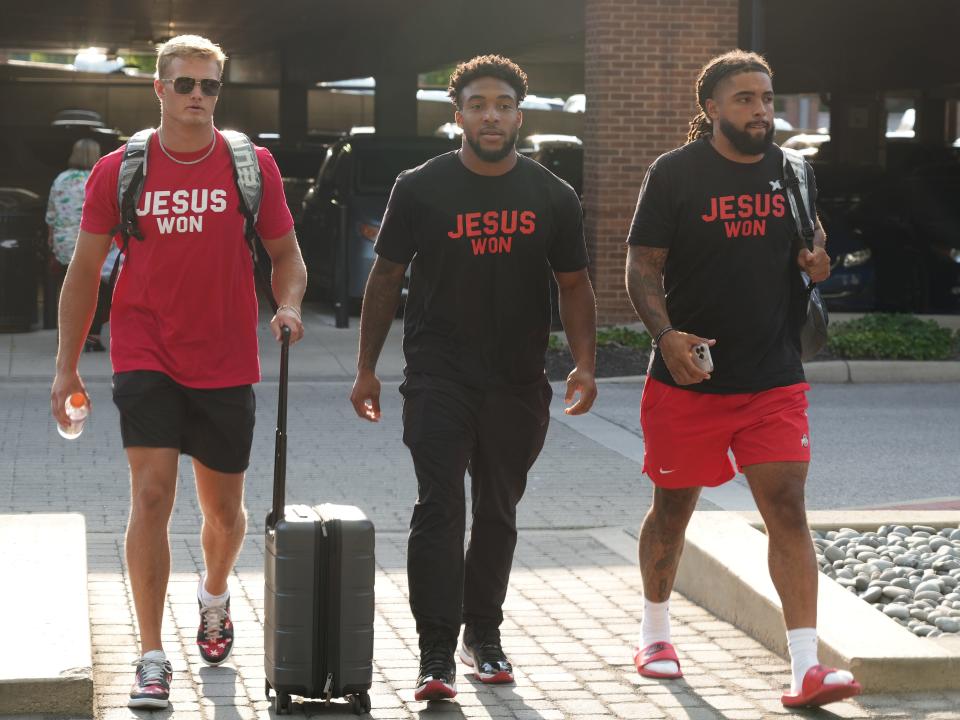 Aug 5, 2024; Columbus, OH, USA; Ohio State University football players (from left) Lincoln Kienholz, TreVeyon Henderson and Gee Scott Jr. walk from the parking garage to their hotel where they will stay during most of the 2024 Fall Camp.