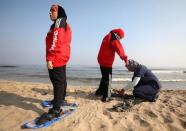 Coach Fatma Ismail fits snowshoes for Special Olympics athletes Alaa Abdelaziz and Esraa Gamal on a beach in Alexandria, Egypt, July 18, 2017. REUTERS/Mohamed Abd El Ghany