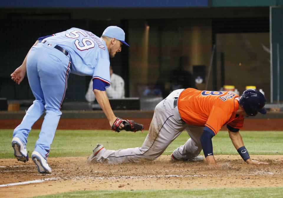 Houston Astros' Jason Castro, right, avoids a tag by Texas Rangers relief pitcher Brett de Geus, left, as he scores on a wild pitch during the eighth inning of a baseball game in Arlington, Texas, Sunday, May 23, 2021. (AP Photo/Ray Carlin)