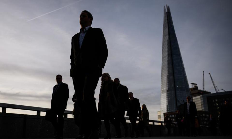 commuters walk across a bridge in london