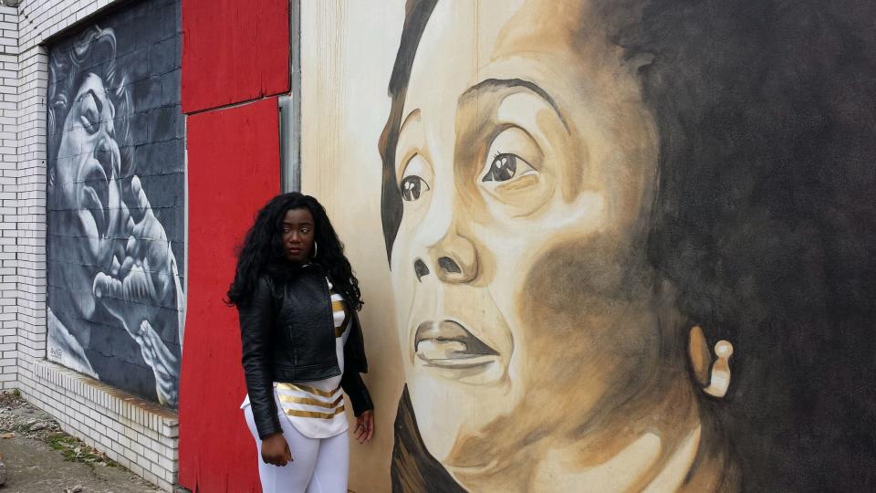 Britney Boateng standing next to a mural of Coretta Scott King in Columbus.