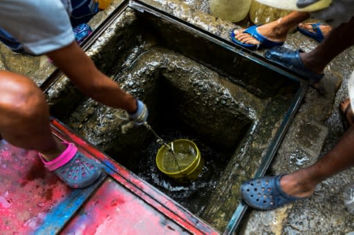 People draw water from a spring water tank to be used in their toilets in Caracas