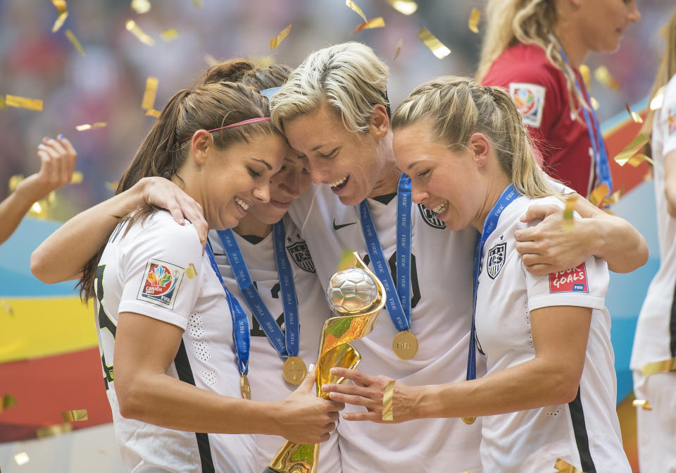 Alex Morgan (left), Lauren Holiday, Abby Wambach, and Whitney Engen celebrate with the World Cup trophy in 2015. (Photo by Christopher Morris/Corbis via Getty Images)