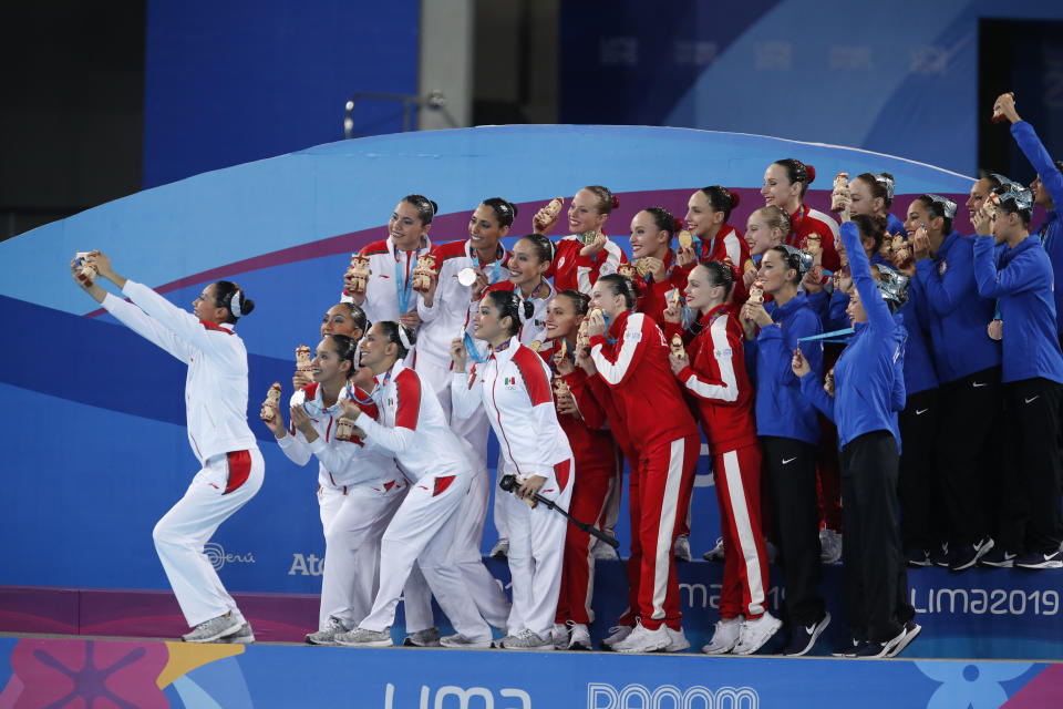 Canada, gold medalists, center, Mexico, silver medalists, left, and the U.S., bronze medalists, right, pose for a selfie after the medals ceremony for team competition free artistic swimming at the Pan American Games in Lima, Peru, Wednesday, July 31, 2019. (AP Photo/Moises Castillo)