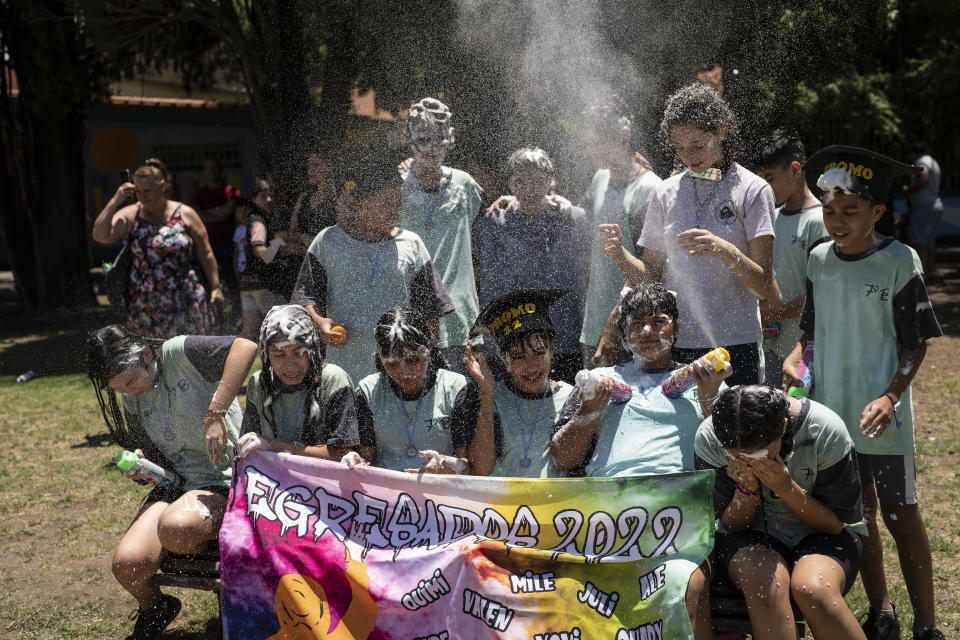 Students graduating from the General Las Heras elementary school, where soccer player Lionel Messi also attended, play with foam as they pose for a group photo on their last day in Rosario, Argentina, Wednesday, Dec. 14, 2022. (AP Photo/Rodrigo Abd)