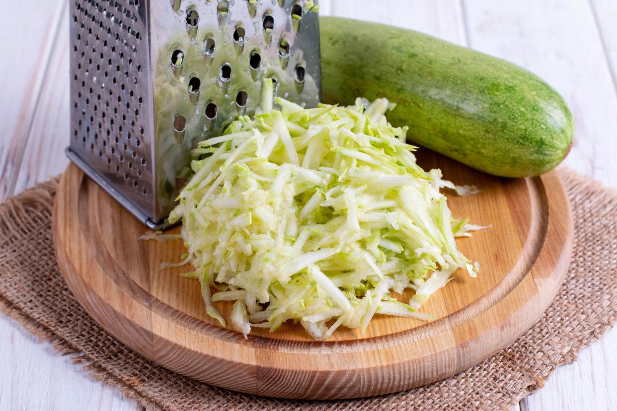 Grated zucchini with grater and wooden board