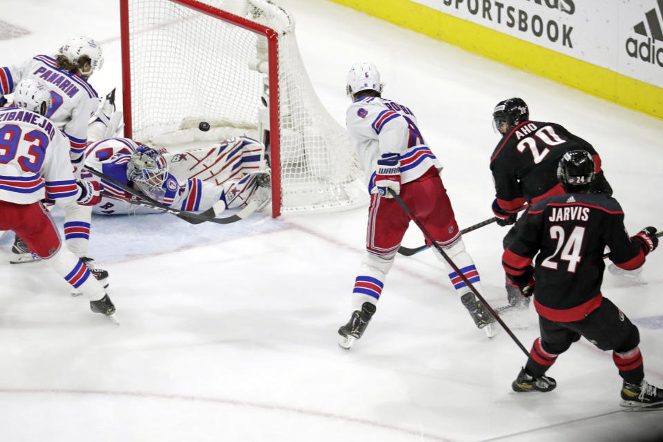 Carolina Hurricanes center Sebastian Aho (20) shoots the puck over New York Rangers goaltender Igor Shesterkin (31) for a goal as center Mika Zibanejad (93) and left wing Artemi Panarin (10) defend during the third period of Game 1 of an NHL hockey Stanley Cup second-round playoff series Wednesday, May 18, 2022 in Raleigh, N.C. (AP Photo/Chris Seward)