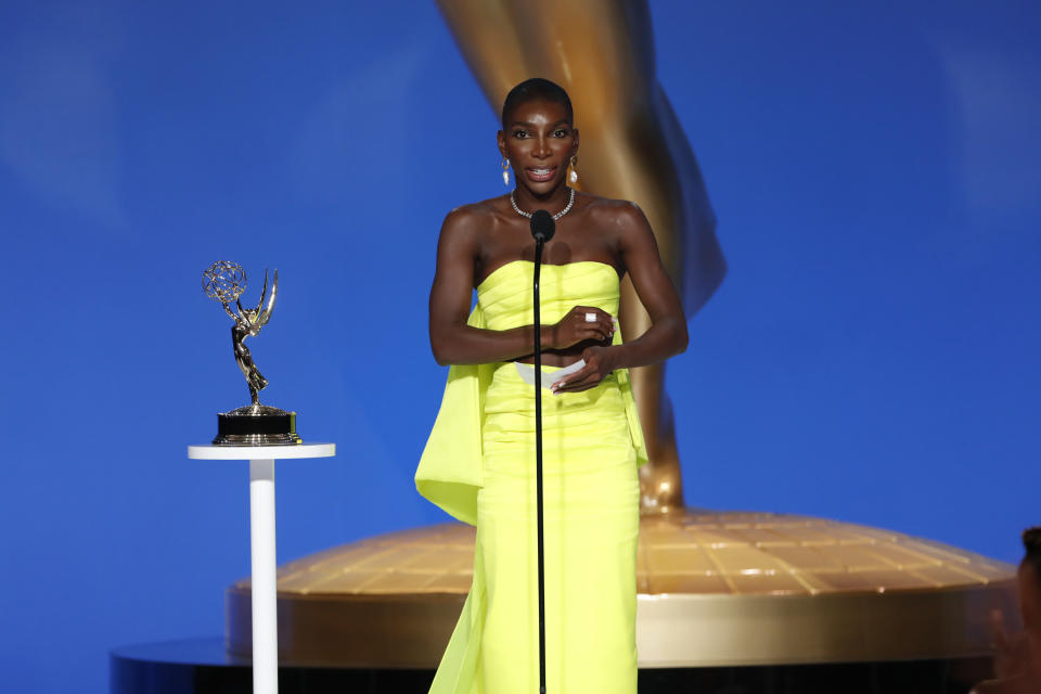 Michaela standing in front of a microphone in a gown