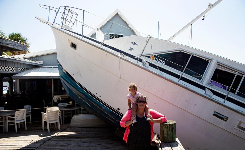 Bonita Bill's co-owner, Katie Reynolds, and her daughter, AnnaKat, stand for a portrait next to the boat, "Bachelor Pad", that broke loose from the docks at Bonita Bill's on Sept. 28, 2022 during Hurricane Ian.