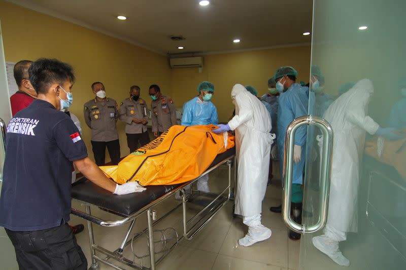 Disaster Victims Identification (DVI) police carry a bag containing the body of a victim of a prison fire in Jakarta