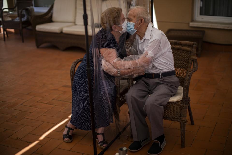 In this Monday, June 22, 2020 photo, Agustina Canamero, 81, and Pascual Pérez, 84, hug and kiss through a plastic film screen to avoid contracting the new coronavirus at a nursing home in Barcelona, Spain. Spain has become the first western Europe to accumulate more than 1 million confirmed infections as the country of 47 million inhabitants struggles to contain a resurgence of the coronavirus. (AP Photo/Emilio Morenatti)