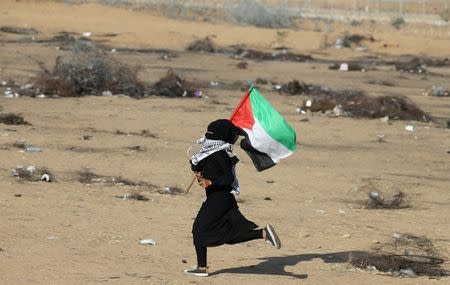 A Palestinian girl runs with a Palestinian flag during a protest at the Israel-Gaza border in the southern Gaza Strip July 6, 2018. REUTERS/Ibraheem Abu Mustafa