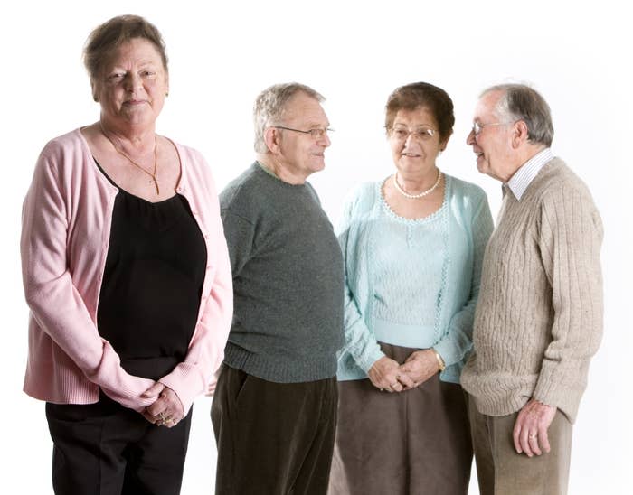 A group of older people wearing sweaters and standing around