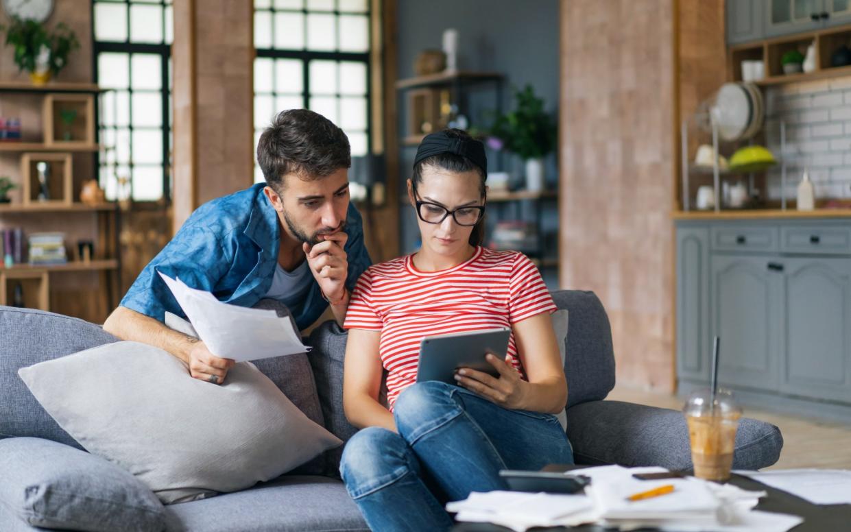 Young couple calculating investments at home using laptop and calculator