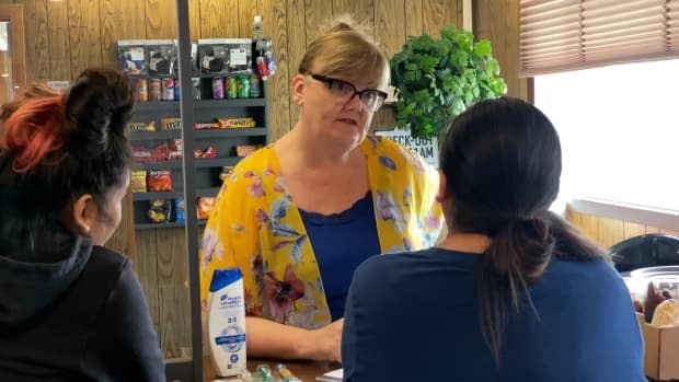 Annette Mason, centre, helps evacuees from Jean Marie River at the front desk of the Snowshoe Inn in Fort Providence, N.W.T. (Travis Burke/CBC - image credit)