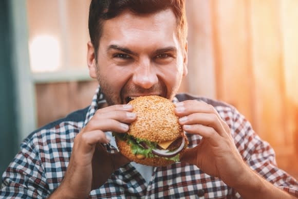 A man biting into a burger.