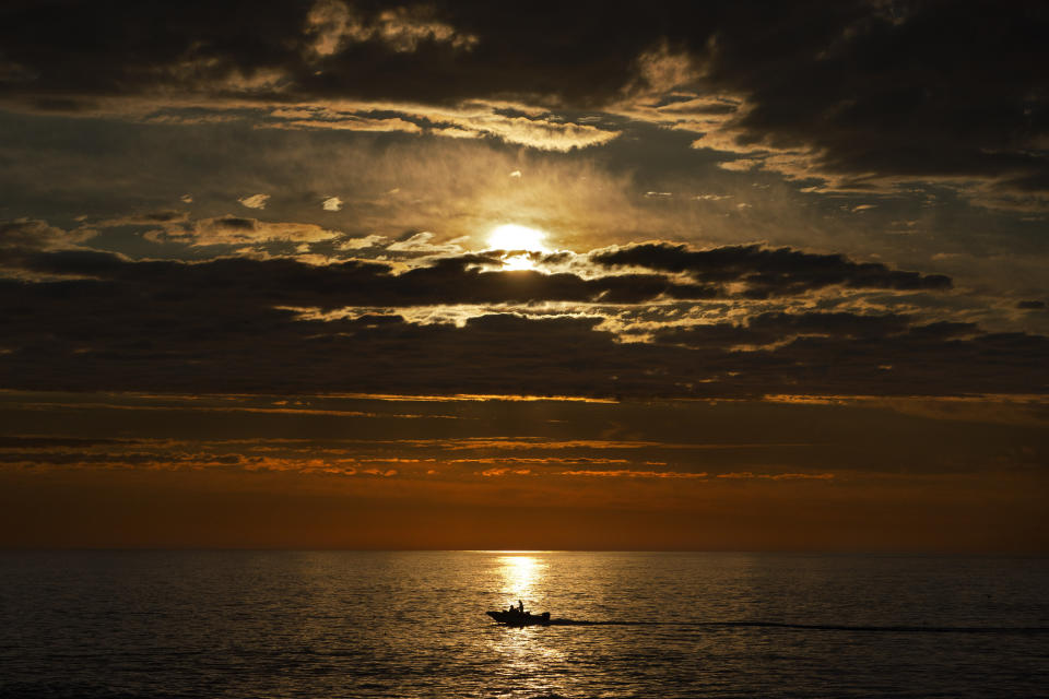 FILE - An early-rising sport fisherman motors over calm seas on his way to striped bass fishing grounds off the coast of Kennebunkport, Maine, July 7, 2022. The continental United States in July set a record for overnight warmth, providing little relief from the day’s sizzling heat for people, animals, plants and the electric grid, meteorologists said. (AP Photo/Robert F. Bukaty, File)