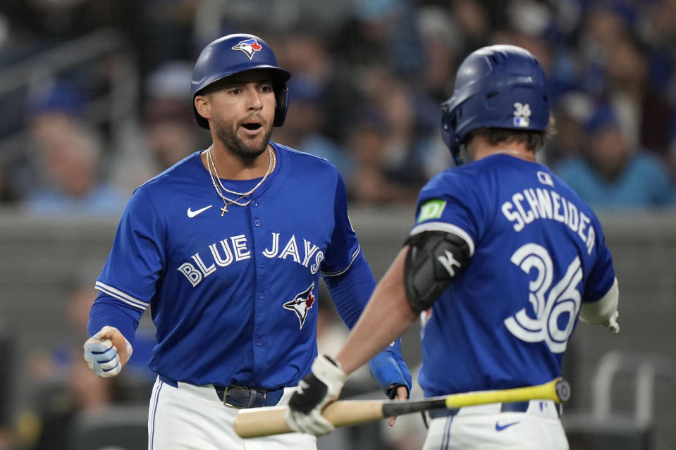 Toronto Blue Jays outfielder George Springer, left, celebrates with teammate Davis Schneider (36) after scoring against the Colorado Rockies during first-inning baseball game action in Toronto, Sunday, April 14, 2024. (Frank Gunn/The Canadian Press via AP)