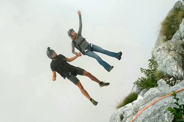 Friends film themselves freefalling backwards from a cliff while hand-in-hand