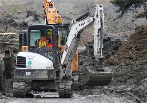 A Washington State Department of Transportation worker helps excavate many feet of mud at the west side of the mudslide on Highway 530 near mile marker 37  in Arlington, Wash., on Sunday, March 30, 2014. Periods of rain and wind have hampered efforts the past two days, with some rain showers continuing today. Last night, the confirmed fatalities list was updated to 18, with the number of those missing falling from 90 to 30. (AP Photo/Rick Wilking, Pool)
