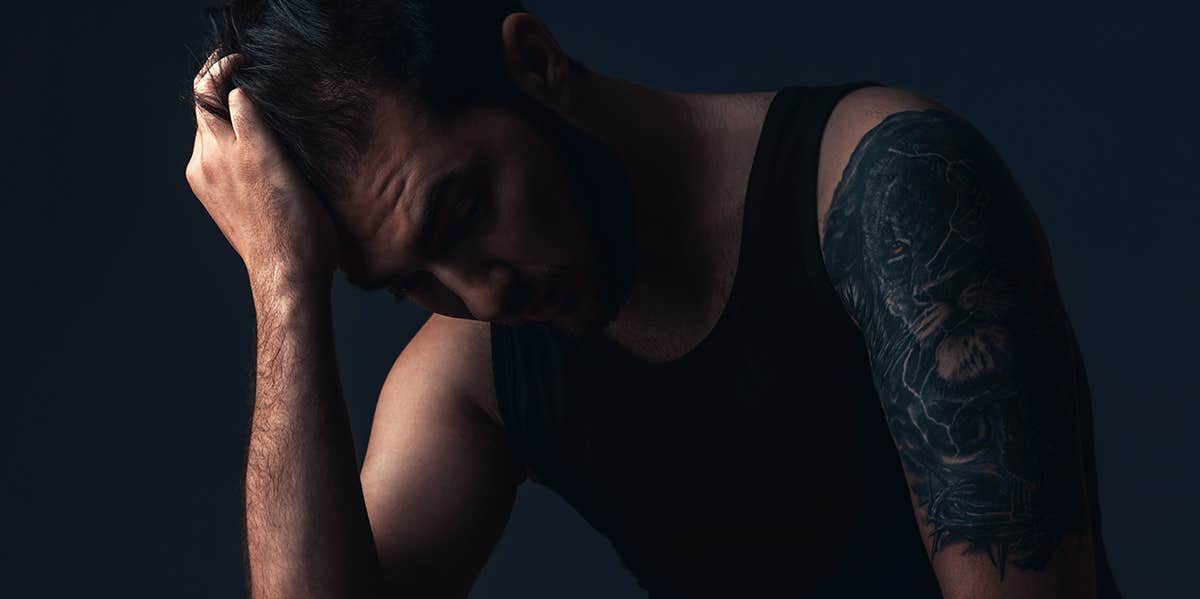 man sitting in dark room with hand on face