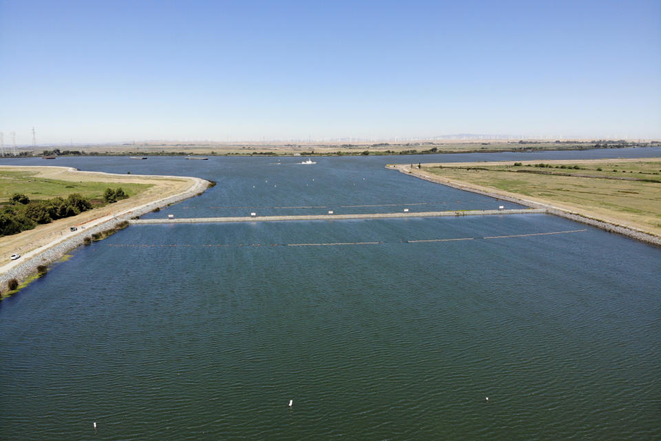 An emergency drought barrier that protects against saltwater intrusion, built by the California Department of Water Resources, stretches across the West False River in the Sacramento-San Joaquin River Delta near Oakley, Calif., Thursday, July 21, 2022. It was supposed to be only temporary, but plans to remove the barrier last fall were scrapped due to dry conditions. Officials still hope to take it out this November. (AP Photo/Terry Chea)