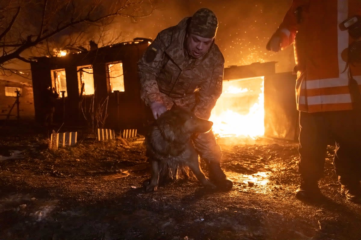 Firefighters rescue a dog as they extinguish a fire following a Russian attack on a residential neighbourhood in Kharkiv (AP)