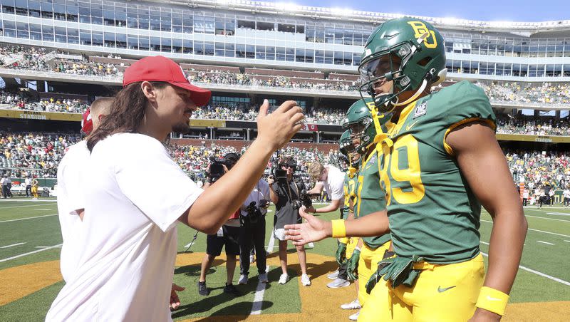 Utah quarterback Cameron Rising, left, greets Baylor tight end Drake Dabney at the coin toss before the game on Sept. 9, 2023, in Waco, Texas. Rising’s status for Saturday’s game against Weber State will be made by his Los Angeles surgeon. 