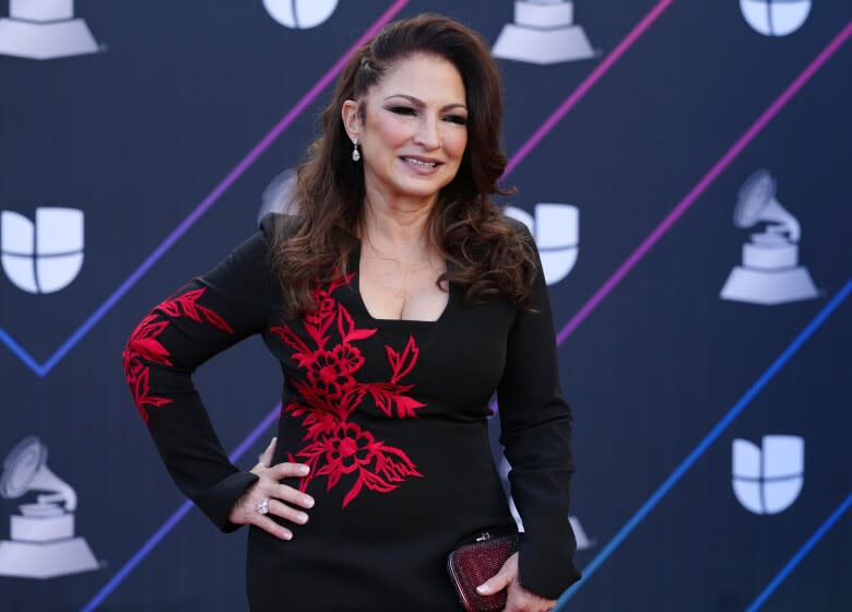 A woman with long red hair posing in a black dress with red accents