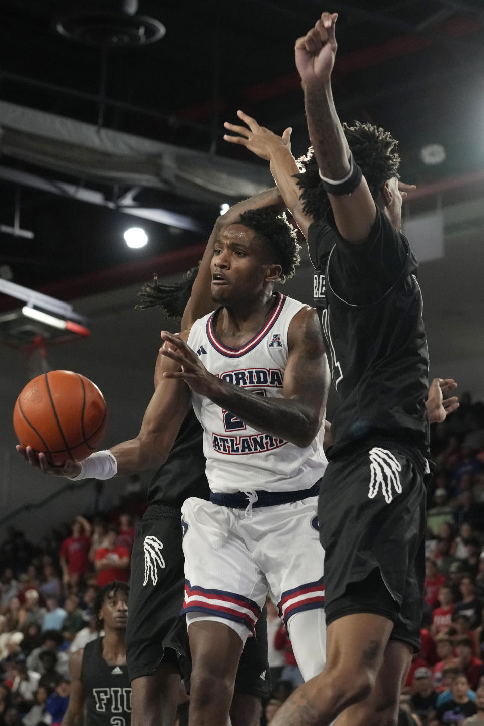 Florida Atlantic guard Brandon Weatherspoon (23) passes the ball under pressure from Florida International guard Jayden Brewer (11) and center Seth Pinkney during the first half of an NCAA college basketball game, Wednesday, Dec. 13, 2023, in Boca Raton, Fla. (AP Photo/Marta Lavandier)