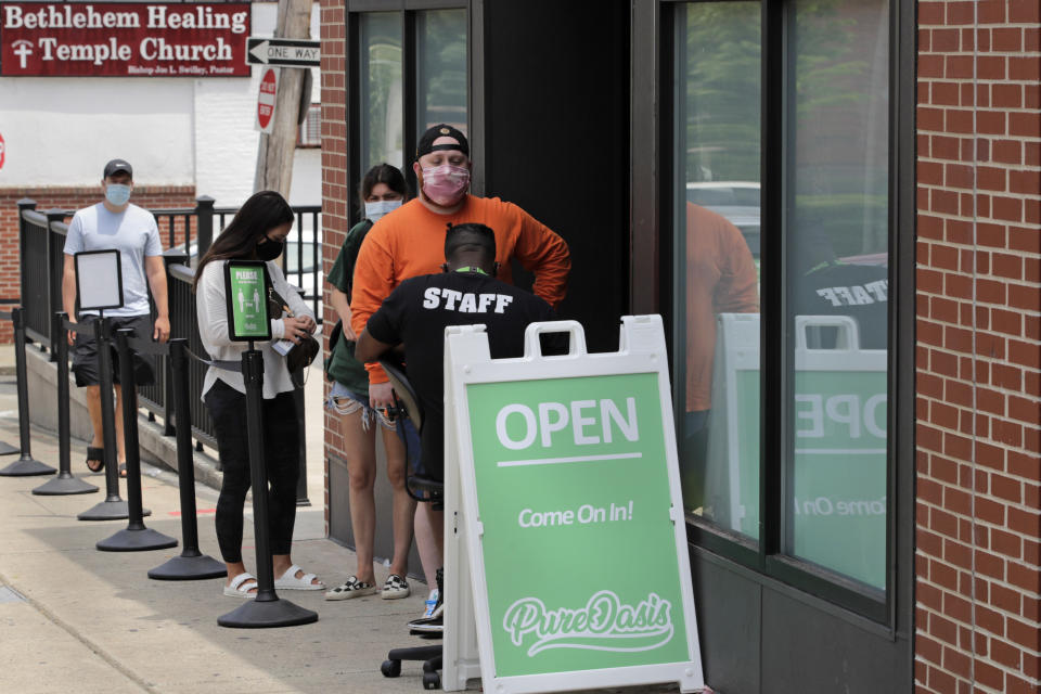 In this Wednesday, June 24, 2020, photograph, customers wait in line at Pure Oasis, a Black-owned recreational marijuana dispensary, in the Grove Hall neighborhood of Boston. Many from outside Boston have recently shopped and supported the store which was robbed and vandalized earlier in the month. (AP Photo/Charles Krupa)