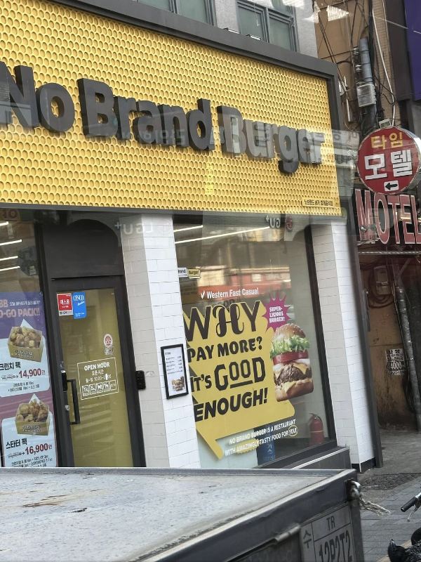 Storefront of 'No Brand Burger' with an advertisement for Western fast food, visible in an urban setting. No persons in image